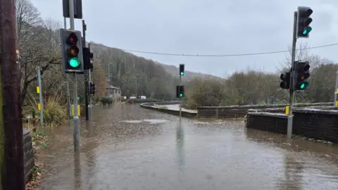 Flooding around a junction between a bridge and a road with traffic lights sticking out of the water.