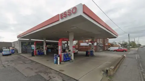 The New Seaham Service Station on Stockton Road. It is an Esso petrol station which is covered with a red and white roof. A small shop stands behind it.