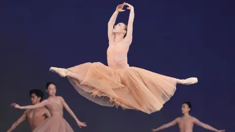 PA Media Members of the Birmingham Royal Ballet performing on the Pyramid Stage, at the Glastonbury Festival. Ballerinas are dressed in peach tutu dresses.