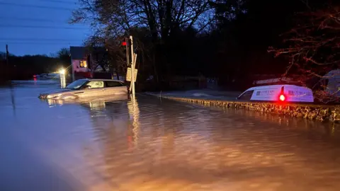 PA Media/Devon and Somerset Fire and Rescue Service A car and a van are submerged in flood waters