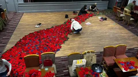 Barnsley Opals Women's Institute A group of people in a large hall working on the poppy cascade