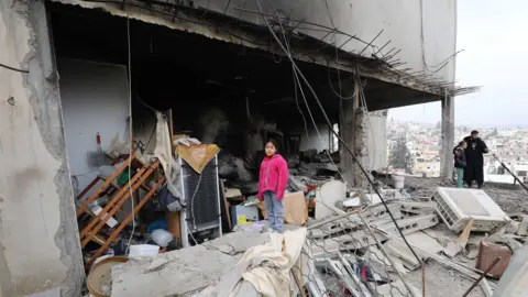 Getty Images Palestinian residents inspect the area among the rubble of damaged buildings