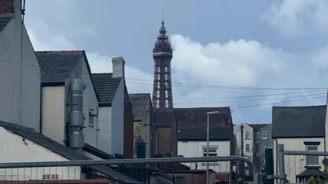 Handout The Blackpool tower against a backdrop of blue sky, with residential buildings in the foreground