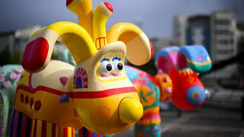 Getty Images A colourfully decorated statue of Gromit from Wallace and Gromit. This one is painted yellow striped legs of different colours.