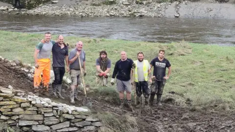 Adrian Langdon Five men working on a stone island on a river bed when the tide is out