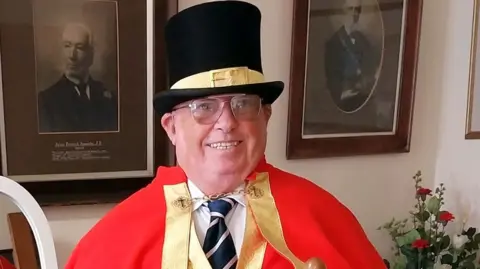 Terrence Mullett Terrence Mullett in town crier regalia - wearing red robes and black top hat and glasses