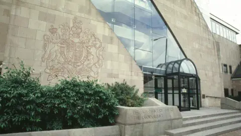 Extérieur du Nottingham Crown Court, composé de briques grises et de cadres de fenêtres sombres.