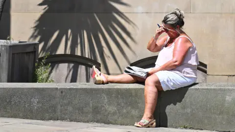 Getty Images A crossword is worked on in the sunshine in the town centre in Huddersfield in Northern England on June 23, 2026, as temperatures increase to heatwave levels and are set to rise further in the week ahead. 