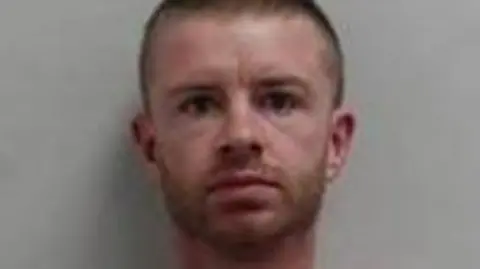 a mug shot of a man with a skinfade and a beard