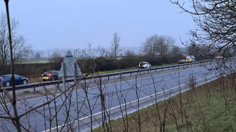 Samantha Hunter Cars parked on the side of a dual carriageway. The picture is taken from the other side of the road to where the cars are parked.