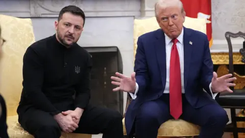 Getty Images Volodymyr Zelensky sits beside a gesturing Donald Trump in the Oval Office of the White House. Zelensky wears dark clothes while Trump wears a blue suit, white shirt and red tie.