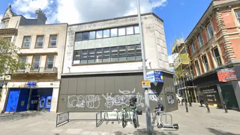 Google A Google Streetview showing the boarded up former McDonald's restaurant. The boarding has graffiti on.