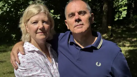 Rodina muž a žena na obrázku v zahradě mají ruce kolem sebe a dívají se do kamery