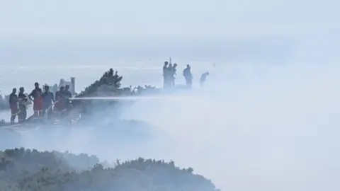 Hampshire and Isle of Wight Fire and Rescue Service Fire crews shooting jets at a smokey area 