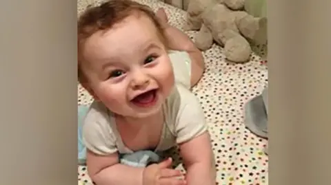 Handout A babe  lies connected  a cot 