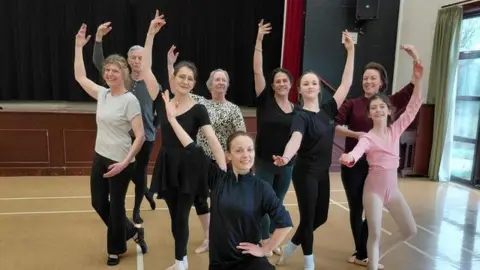 Lianne Carter A group of people rehearsing a dance routine inside a large hall.