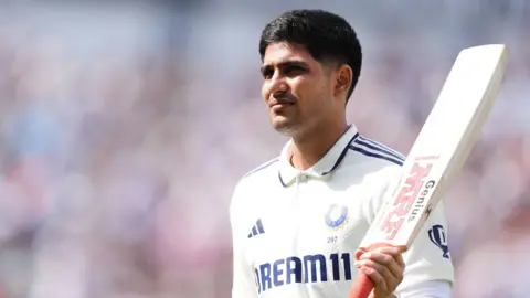 Shubman Gill raises his bat after hitting a century