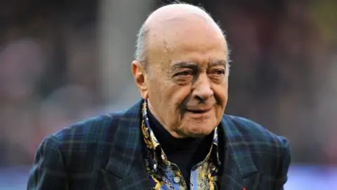 PA Media Mohamed Al Fayed wearing a dark green tartan jacket and black, blue and yellow printed shirt with a black turtle neck jumper underneath