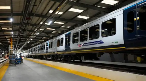 PA Me Train carriages painted with the new GBR livery and logo, they have been raised on a platform of some kind.