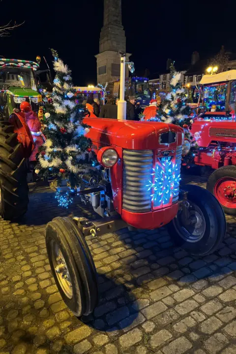 North Yorkshire Police, Harrogate area A vintage red tractor covered in tinsel, lights and Christmas trees in Ripon's market square at night 