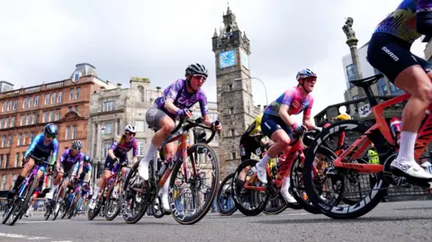 PA Media Riders pass the Tolbooth Steeple at Glasgow Cross during stage four of the 2025 Lloyds Tour of Britain