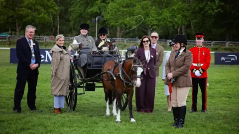 Princess Sophie can be seen giving Rebecca Stevens a cup. They are both in formal wear on the grounds of at Royal Windsor Horse Show.