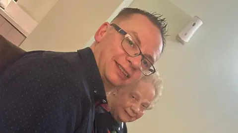 Family handout An up close picture of Gareth and his granny Ellen. Gareth is pictured with dark brown hair with his fringe spiked up, he is wearing a pair of rectangular glasses. He has a navy top on with small polka dots throughout the shirt. His granny Ellen is slightly behind him on the right hand side of the picture she has a black round neck jumper on with white hair blow-dried back out of her face her hair is shorter in length. 