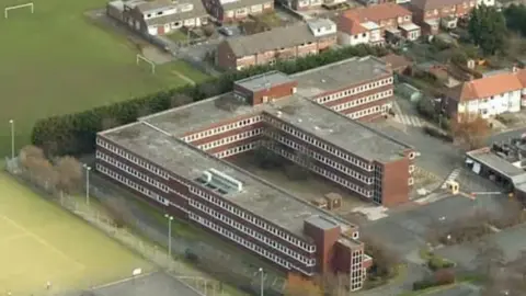 LDRS Aerial view of Mexford House. A large three storey building in the shape of a back-to-front letter 'F' in ted brick with white windows and a flat roof