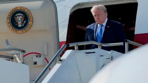 Trump leaving Air Force One through the door at the top of the steps to the plane.