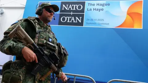 Reuters An armed soldier stands in front of a blue Nato logo