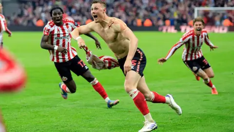 Getty Images Dan Ballard's goal in the semi-final of the Championship playoffs. He's taken his shirt off in celebration and runs to celebrate with the fans at the Stadium of Light.