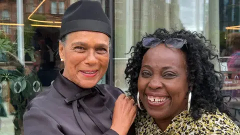 Michelle Adamson/BBC Pauline Black (left) is clad in black complete with a black hat. Ruby Turner has black curly, large earrigns, and sjhaeds on her forehead. She wears a printed coat.