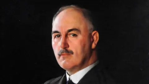 David Jagger/the artist's estate A painting of a man with greying hair and a black moustache, wearing a winged collar white shirt, a black tie and black suit jacket