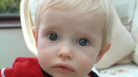 A close up of Elliot with blue eyes in front of a chair