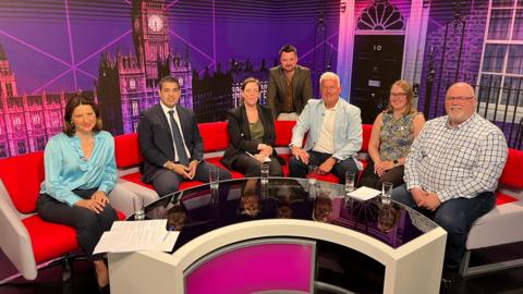 Left to right: BBC presenter Sarah Julian, Conservative Ashvir Sangha, Labour's Jess Phillips, BBC Birmingham political reporter Simon Gilbert, Reform UK's Mark Hoath, the Green Party's Jane Baston and Liberal Democrat Lee Dargue. They are sitting on a red sofa in a TV studio.