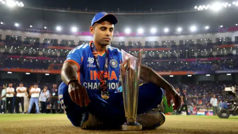 India captain Suryakumar Yadav sits on the pitch looking at the T20 World Cup trophy in front of him
