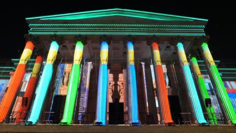 A light show is projected on to the side of the National Gallery