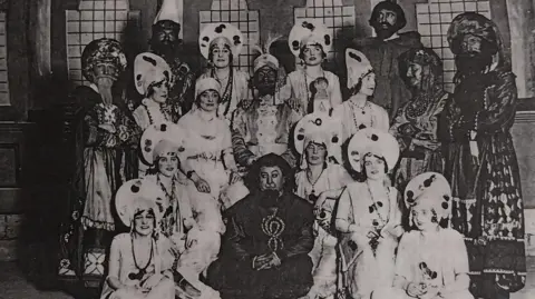 PODS A black and white photo of the PODS cast of Rose of Persia dressed in costume in 1928