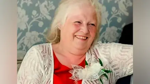 Family handout Esther Martin, who is wearing a red top and white cardigan with a flower pinned to it. She is smiling.