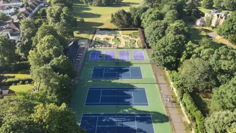 Oxford City Council A drone view of Bury Knowle Park on a sunny day. The tennis court is visible, as well as the mini gold area.