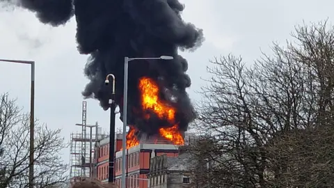 Plumes of black smoke billow into the sky as a fire sweeps through a construction site of new flats on Parliament Street, Lancaster