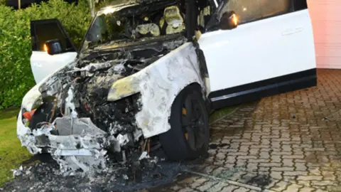 COPFS The white Land Rover is parked in a driveway. It has been badly damaged by fire