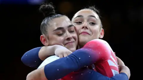 Getty Images A close up of twin athletes as they embrace on stage while wearing UK red, white and blue outfits