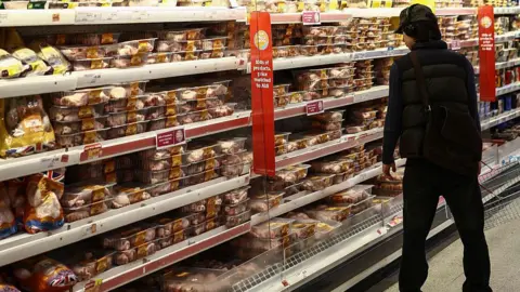 A young man in the meat aisle of a supermarket