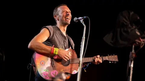Chris Martin smiles as Coldplay perform at Glastonbury 2024