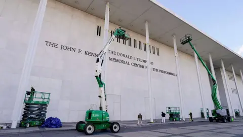 Bloomberg via Getty Images Trabalhadores do lado de fora do Kennedy Center, no elevador em frente ao prédio, onde uma placa agora diz 