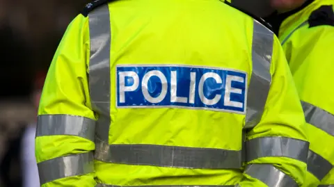 Getty Two officers stood in hi vis yellow jackets. The image only shows one back which says 'police' on and another officer stood next to them, you cannot see their faces.