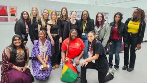Eastern Education Group Nail artist Shea with a group of 14 pupils in a white gallery space.