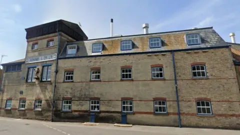 Google Maps The outside of Adnams' brewery in Southwold. A large brick three-storey building with sash windows. It has a sign reading "Adnams & Co Ltd". 