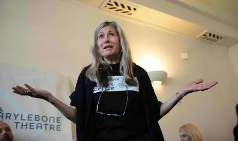 Gavin Watson Woman with arms outstretched and glasses on a chord around her neck.